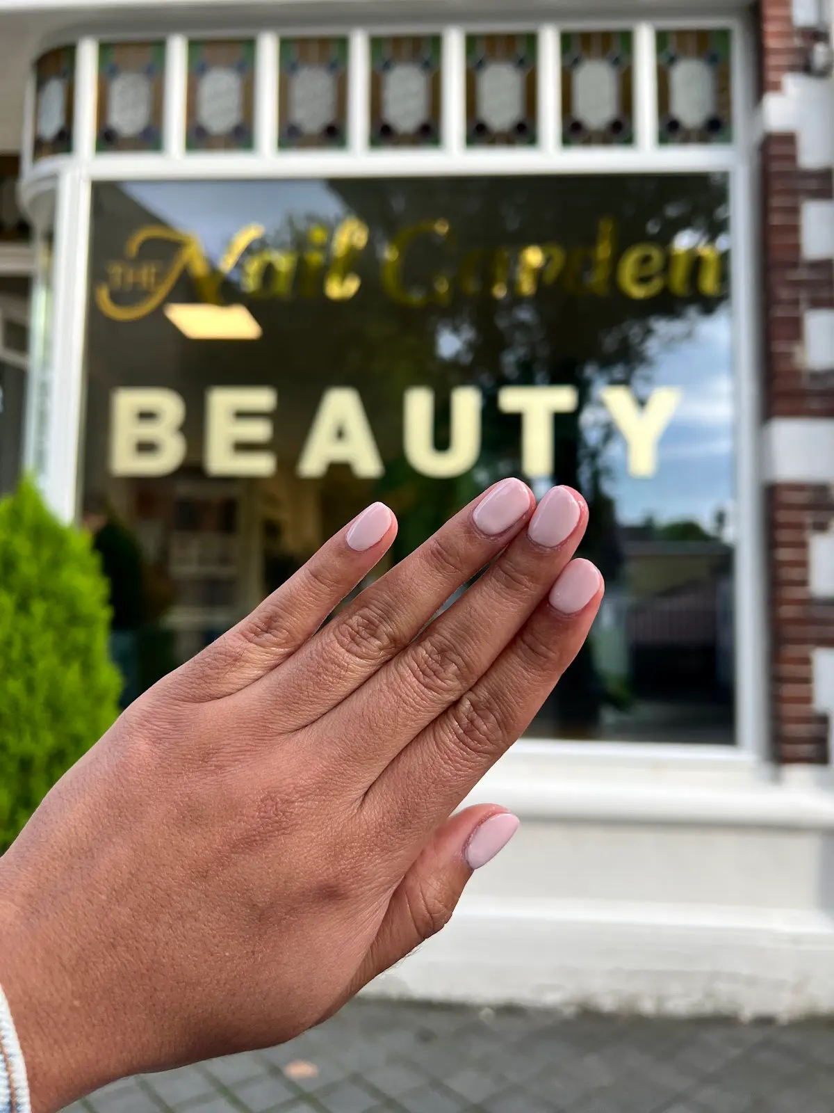 Nude nagels voor het raam van de salon aan de Lindenlaan