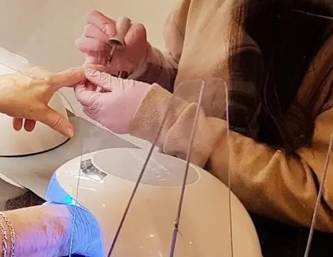 Handen aan het werk: de nagels van een klant worden gelakt, met de lamp ernaast
